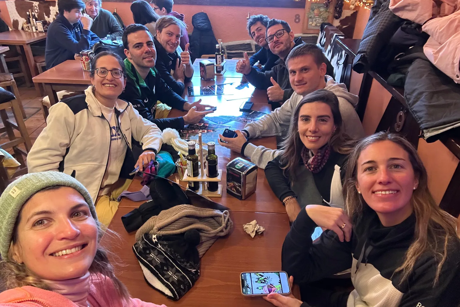 Friends round a long table at a bar, splitting the night out