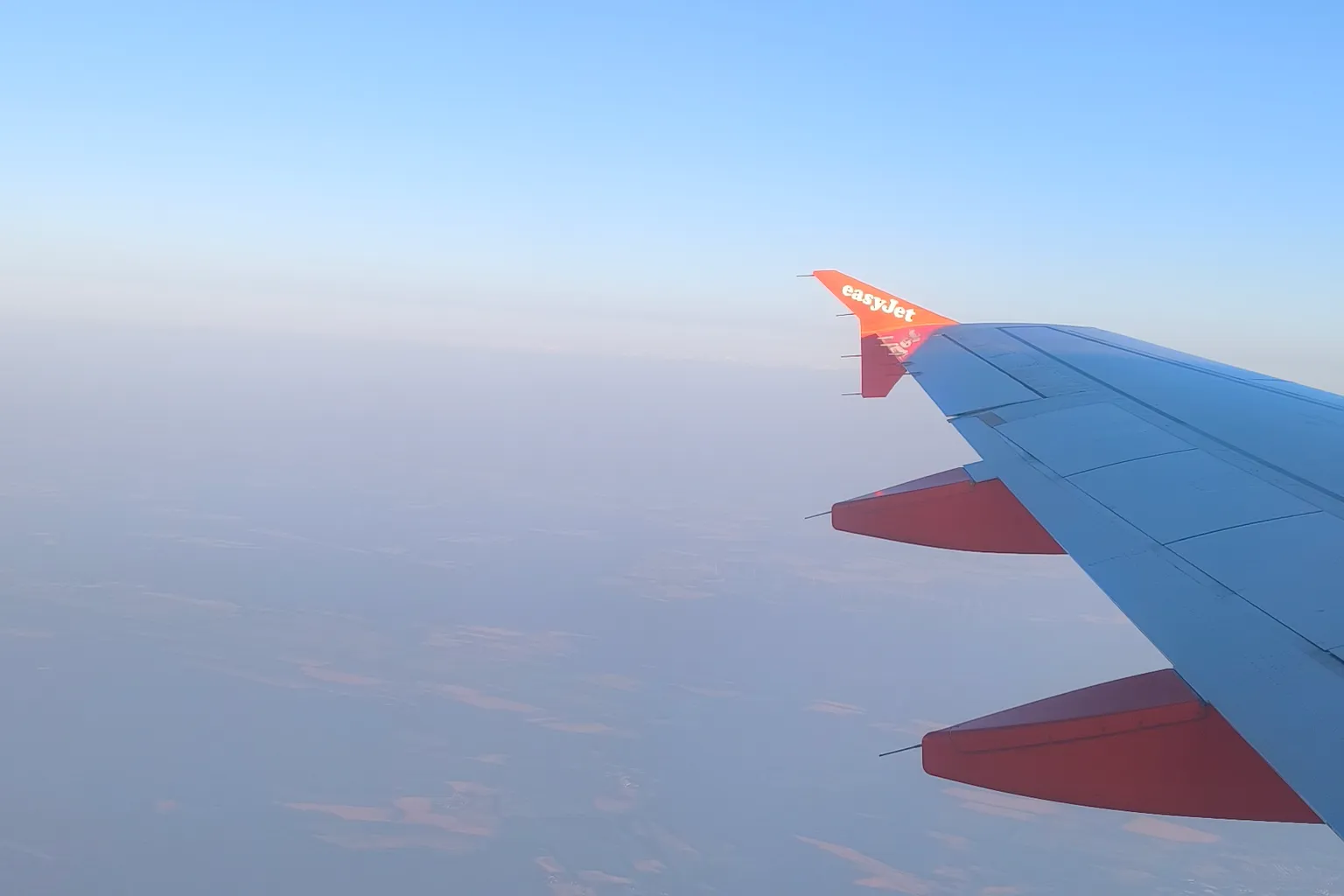 An aeroplane wing over farmland on the way to a weekend away